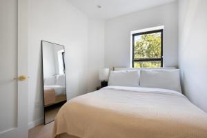 a white bedroom with a bed and a mirror at Blueground Greenpoint view nr McGolrick Park NYC-2071 in Brooklyn