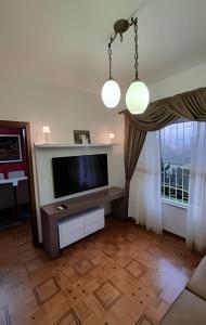 a living room with a flat screen tv and a table at Casa Central com Vista Exclusiva in Pomerode