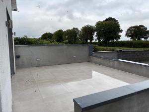 an empty patio with a concrete wall and trees at The Overlook in Cahir
