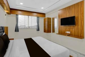 a bedroom with a bed and a flat screen tv at Hotel O Anand guest house in Vastral