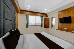 Un dormitorio con una cama y un televisor de pantalla plana. en Hotel O Anand guest house, en Vastral