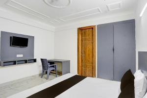 a bedroom with a bed and a desk and a television at Hotel O Dk Hotel in Okhla