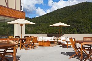 eine Terrasse mit Tischen, Stühlen und Sonnenschirmen in der Unterkunft Hotel Granja Brasil Resort in Itaipava