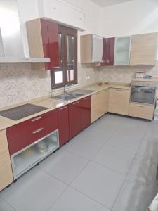 a kitchen with red cabinets and a white tile floor at Nina's house, nonno pepè in Isca Marina