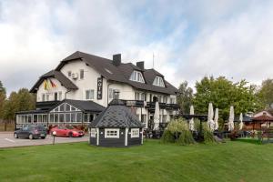 a large white building with a small house in the grass at Butenas Hotel Tyla in Biržai