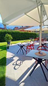 a group of tables and chairs with an umbrella at Hotel Villa Cuserina in Cannobio