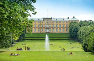 a large building with people in the grass in front of it at Stylish Apartment with Rooftop in Trendy Vesterbro in Copenhagen