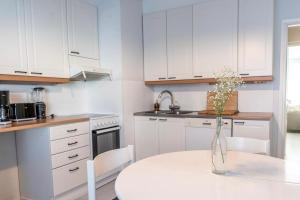 a white kitchen with a table and a vase with flowers at Downtown Rovaniemi, Perfect Location in Rovaniemi