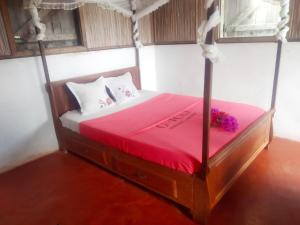 a bedroom with a bed with a red comforter at Le pied dans l'eau in Aniribe