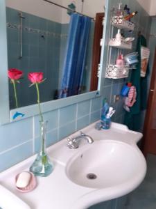 a bathroom sink with a vase with a rose in it at Room country-lake in Dormelletto