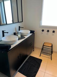 a bathroom with two sinks on a counter with a stool at Cap Coz Cottage 4* a 500 m de la plage de sable fin in Fouesnant +24 photos