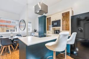 une cuisine avec des chaises blanches et un îlot bleu dans l'établissement Contractor Ready with parking in S10, sleeps 6, à Walkley