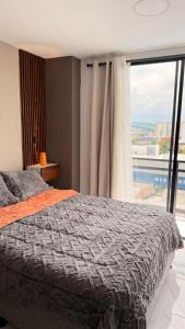a bedroom with a bed and a large window at Moderno apt con vista a la ciudad y estilo único in Pereira