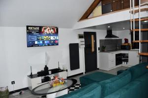 a living room with a green couch and a tv at Eden House in Saint-Pierre-Canivet