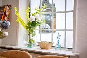 a window with vases and flowers on a window sill at Quaint 200 year old cosy characterful cottage in Swanland +44 photos