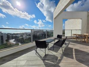 a balcony with chairs and a table on a building at Hantke22• Horev Penthouse • Jacuzzi • 4BD in Aẖuzzat Shemu‘el