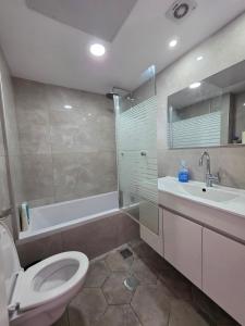 a bathroom with a toilet and a sink and a tub at Hantke22• Horev Penthouse • Jacuzzi • 4BD in Aẖuzzat Shemu‘el +33 photos