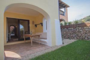 a patio with a table and a stone wall at Beautiful Giardino Degli Oleandri-1BedApt BILO4 in Liscia di Vacca