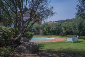 a swimming pool in a yard with a tree and rocks at Beautiful Giardino Degli Oleandri-1BedApt BILO4 in Liscia di Vacca
