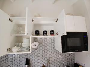 グランド・アンスにあるAtrium Apartments - Sorrel Loftの白いキャビネットと黒い電子レンジ付きのキッチンが備わります。 +2枚の写真