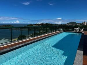 a swimming pool with a view of the ocean at Flat Praia Comfort Camburi in Vitória