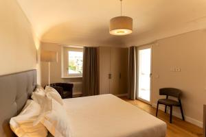 a bedroom with a bed and a chair and a window at Vinea Relais in Dogliani +25 photos