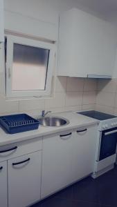 a white kitchen with a sink and a stove at Family Apartman Telep Novi Sad - Yard & Free parking in Novi Sad +8 photos