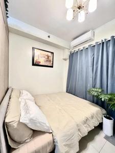 - un lit dans une chambre dotée d'un rideau bleu dans l'établissement Lanzon Azure Urban Resort Staycation, à Manille