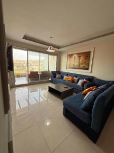 a living room with a blue couch and a table at Élégance et Sérénité Vue Mer Panoramique et Piscine Privée in Agadir
