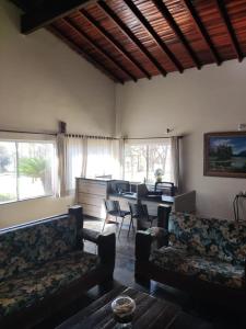 a living room with couches and a table and windows at Pousada Tropical Vereda in Olímpia
