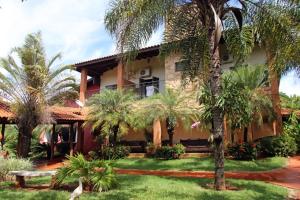 a house with palm trees in front of it at Pousada Tropical Vereda in Olímpia