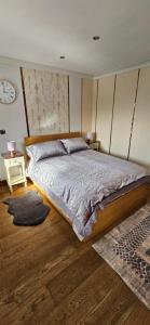 ein Schlafzimmer mit einem großen Bett und einer Uhr an der Wand in der Unterkunft Cosy Studio Quest House in Romford