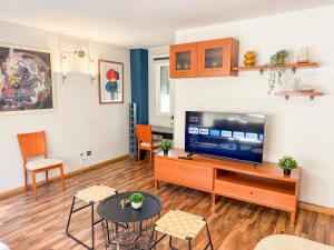 een woonkamer met een televisie en een tafel en stoelen bij Cineasta del Pilar - Turistea in Zaragoza