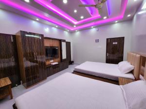 una camera con 2 letti e illuminazione viola di Saha Guest House & Restaurant a Krishnanagar