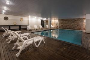 a pool with white lounge chairs and chairs next to it at Golden Beach Resort & Spa in Punta del Este