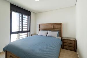a bedroom with a blue bed and a window at Ayla Oasis Golf Apartment - Ayla Vista in Aqaba