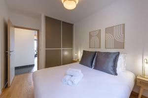 a bedroom with a large white bed with towels on it at Le Cosy Azura - Appartement de charme au coeur de Sévrier & vue lac in Sévrier