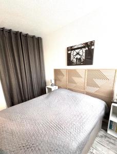 a bedroom with a bed and a clock on the wall at T2 Familial - 250 m front de mer, plage, seaquarium - parking privé - Bienvenue en occitanie in Le Grau-du-Roi