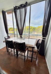 a table and chairs in a room with a large window at T2 Familial - 250 m front de mer, plage, seaquarium - parking privé - Bienvenue en occitanie in Le Grau-du-Roi