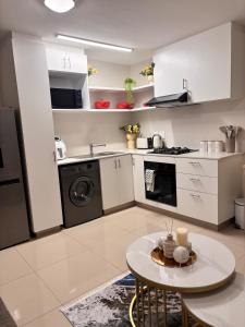 a kitchen with white cabinets and a small table in it at The Cozy Maldives in Durban