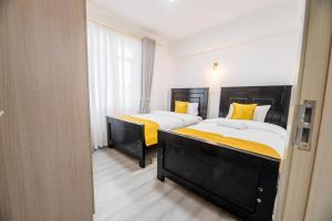 two beds in a hotel room with yellow pillows at Havena Homes-3 Bedroom Apartment at Kilimani in Nairobi +5 photos