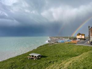 a rainbow over the ocean with a picnic table on a hill at L'Escale, Studio cosy 15m2 avec vue mer, idéal couple - Ault in Ault