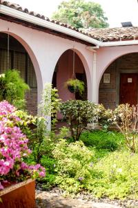 a house with a bunch of flowers in the yard at Hostal Casa del Sol in Suchitoto +16 photos