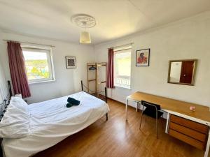 Un dormitorio con una cama blanca y un escritorio. en Spacious 3 Bedroom Flat, en Edimburgo