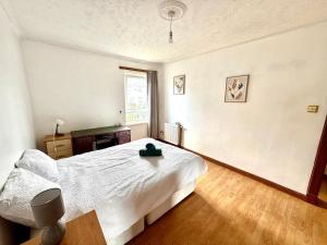 Un dormitorio con una cama blanca y una ventana. en Spacious 3 Bedroom Flat, en Edimburgo