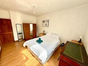 1 dormitorio con 1 cama blanca grande y suelo de madera en Spacious 3 Bedroom Flat, en Edimburgo