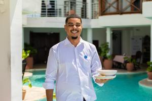a man in a white shirt holding a bowl at ZAN Tropical Island in Bwejuu