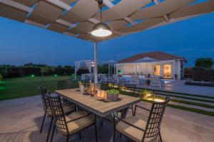 a wooden table with chairs and an umbrella on a patio at Madini Luxury villa with private heated pool in Vanáton