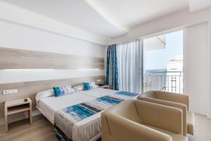 um quarto com uma cama, 2 cadeiras e uma janela em Hotel Gracia em El Arenal