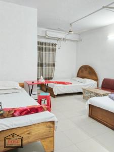 a room with three beds and a table in it at Hotel Rose International in Dhaka